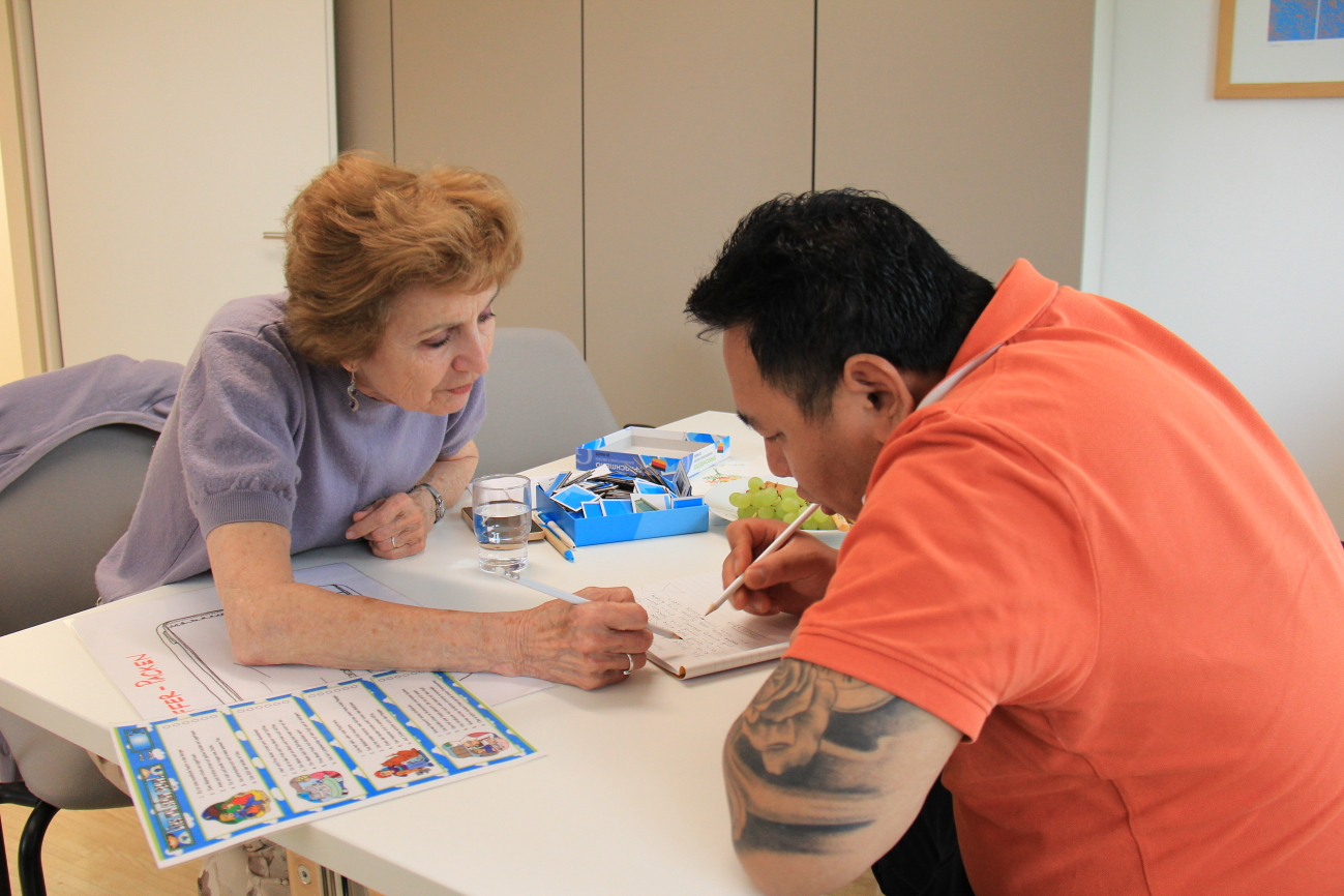 Eine Sprachtrainerin übt mit einem jungen Mann Deutsch